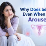 Worried woman sitting on a bed with medical illustrations about pelvic pain and the question of painful sex despite arousal.
